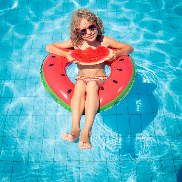 criança comendo melancia em uma melancia inflável na piscina