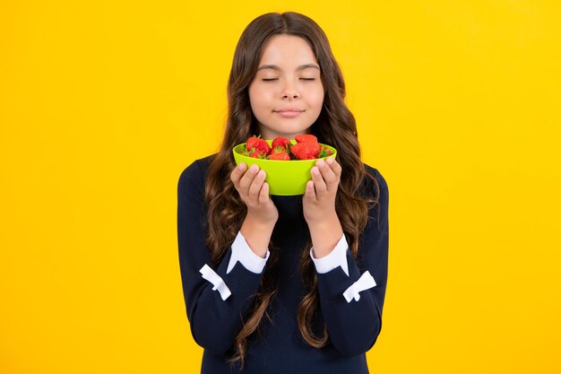 Criança comendo morangos Criança adolescente sorridente feliz segura tigela de morango em fundo amarelo Comida saudável de vitamina orgânica natural para crianças temporada de morango