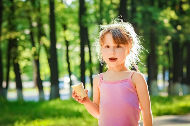 Criança comendo sorvete no parque ao fundo