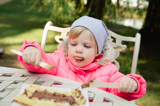 Criança comendo waffles com chocolate