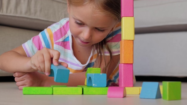 Foto criança concentrada em casa brincando com blocos de madeira coloridos na educação de flores.