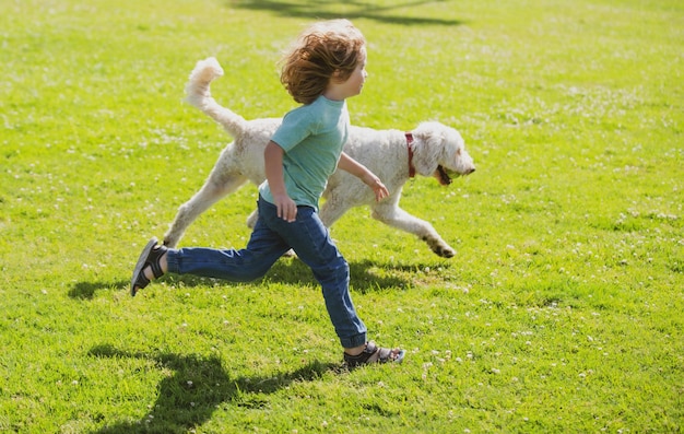 Criança correndo com um cachorro no parque garoto com um cachorrinho ao ar livre brincando no gramado do quintal