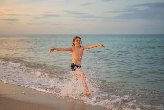 Criança correndo e salpicando no mar ativa criança pequena correndo ao longo da praia do mar criança atividade esportiva