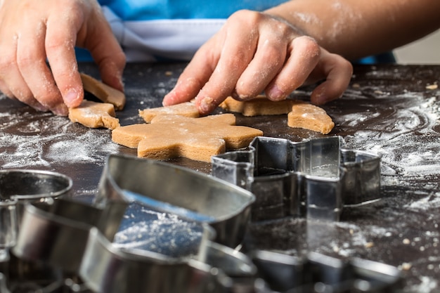 Criança cortar biscoitos da massa na cozinha de casa