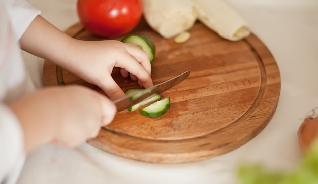 Criança cortar legumes para salada