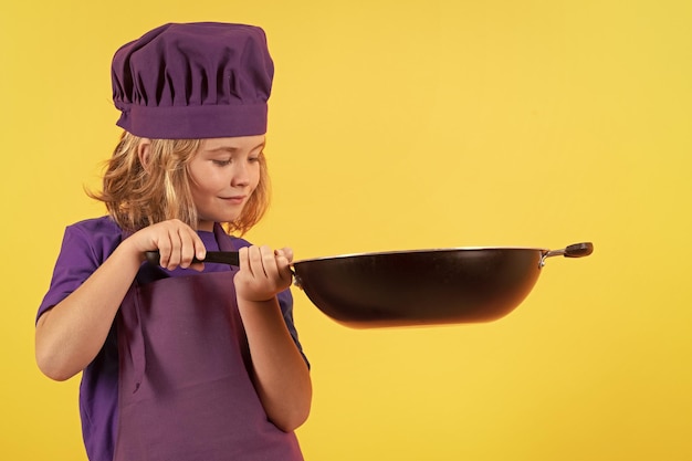 Criança cozinheira com panela de cozinha Criança em uniforme de cozinheira Criança isolada em fundo amarelo Criança bonita