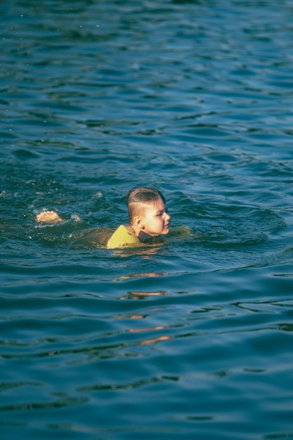 Criança criança nadando no lago com braços infláveis ajuda a apoiar