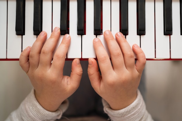 Criança criativa toca o sintetizador. Menina aprendendo a tocar piano.