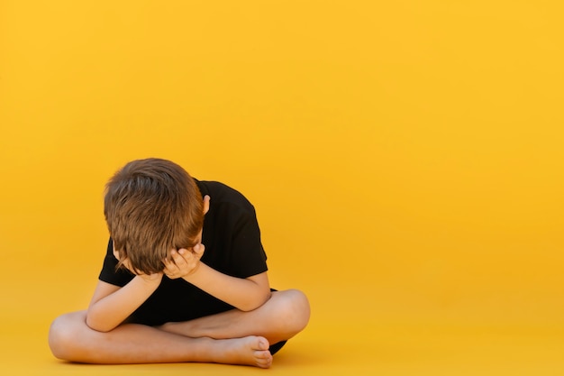 Foto criança cuja depressão está sentada no chão colorido