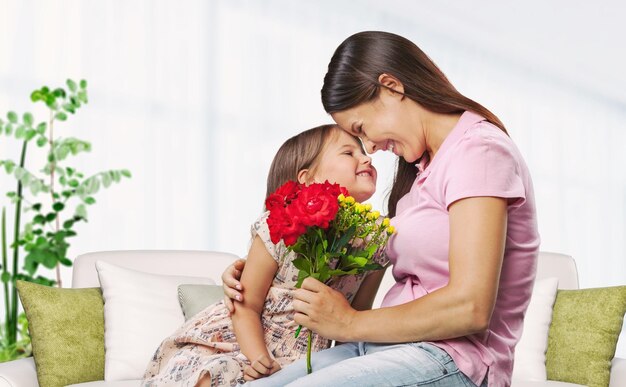Criança cumprimentando a mãe com o Dia da Mãe em casa e dando-lhe um buquê de flores frescas