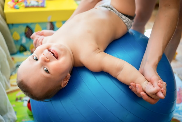 Criança curtindo exercícios na grande bola azul de fitness