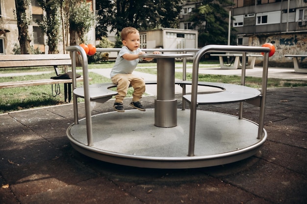 criança de 2 a 3 anos está girando em um carrossel no playground