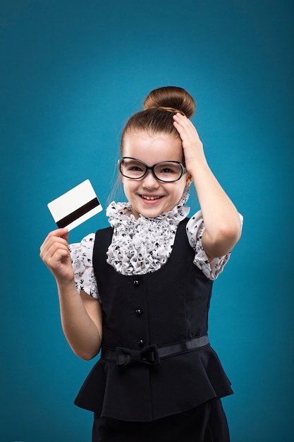 Criança de cabelos escuros com cartão de crédito, vestida como professora de vestido preto