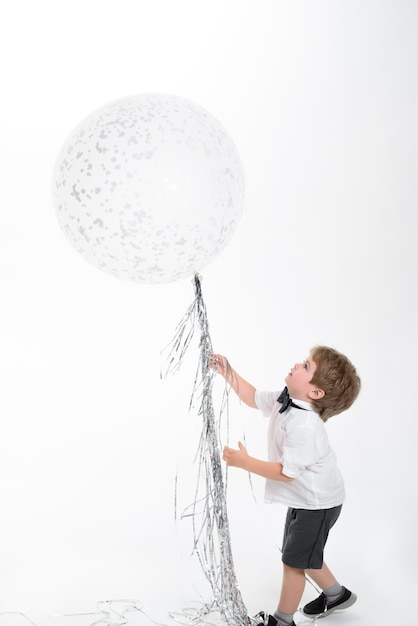 Criança de infância com balão grande festa humor celebração conceito grande balão branco menino brincar com o vôo