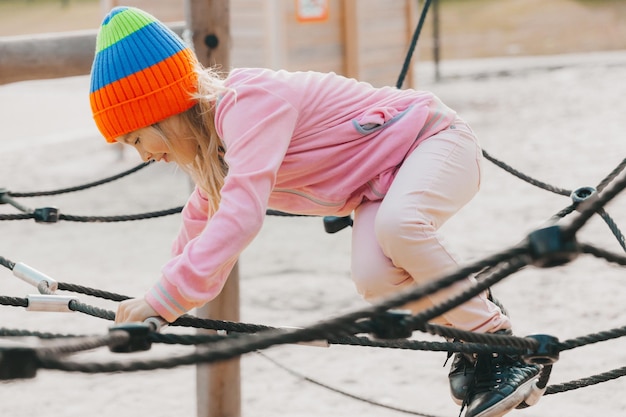 Criança de menina adolescente feliz brincando na teia de aranha de corda no playground. esportes infantis.