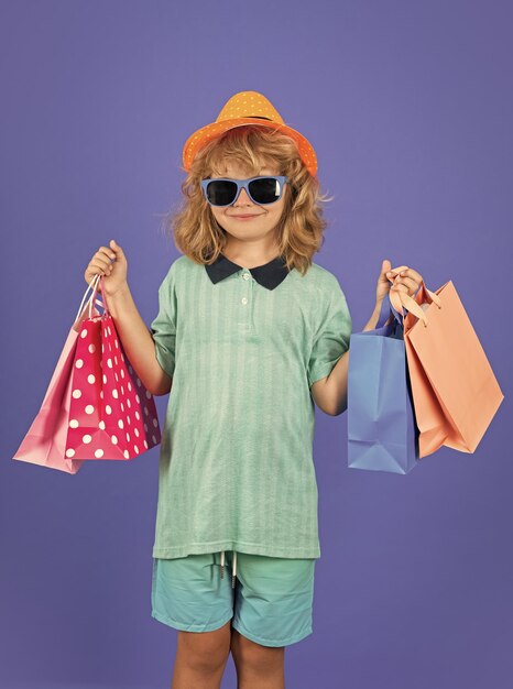 Criança de moda nas compras Retrato de uma criança com sacos de compras Menino feliz segurando sacos de compra Retrato de estúdio
