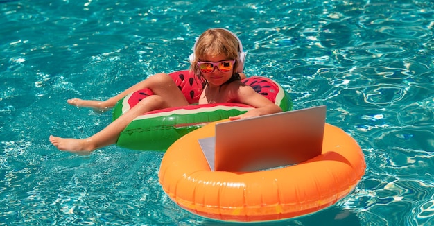 Criança de negócios de verão trabalhando remotamente em laptop na piscina pequeno homem de negócios trabalhando online em laptop