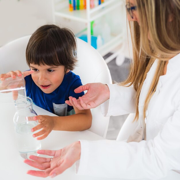 Criança de psicologia infantil fazendo testes com água e copos