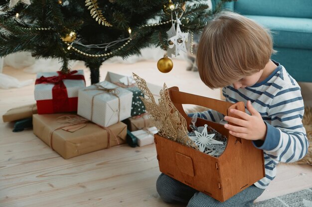 Criança decorando uma árvore de Natal sentada de pijama no interior de uma casa