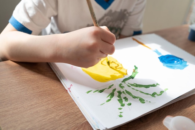 Criança desenha abacaxi com tintas no álbum de perto