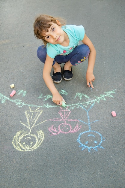 Criança desenha uma família na calçada com giz Foco seletivo