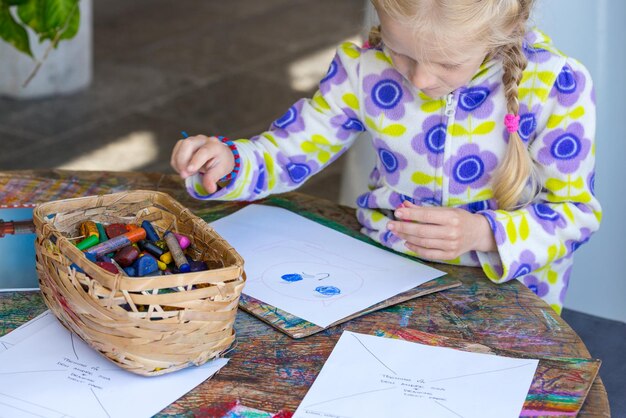 Criança desenhando um pastel no papel