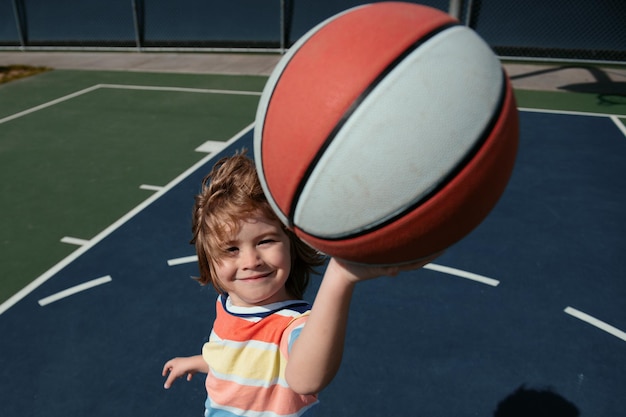 Criança desportiva, caucasiana, a jogar basquetebol, a segurar uma bola com uma cara engraçada