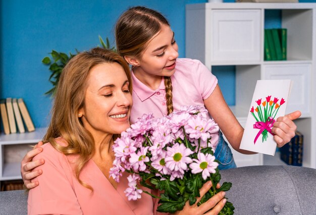 Foto criança do sexo feminino apresentando flores para a mãe em casa, momentos felizes da vida doméstica