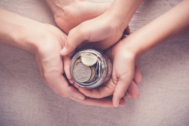 criança e adulto segurando o dinheiro jar, doação, salvando o conceito