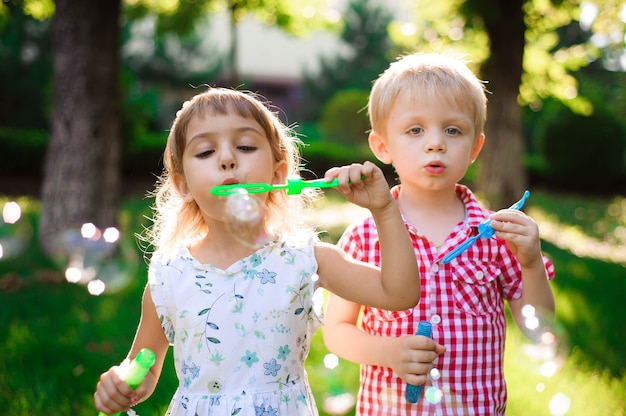 Criança e amigos brincam com uma bolha no playground com fundo do sol, criança, criança, escola, jogo e fundo de verão