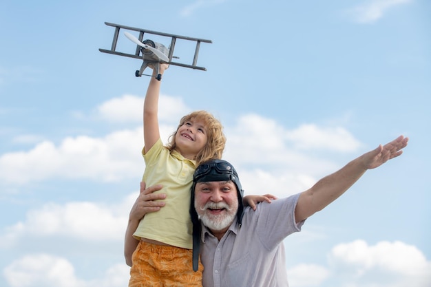 Criança e avô brincando com avião de brinquedo contra o fundo do céu de verão Fim de semana com o avô