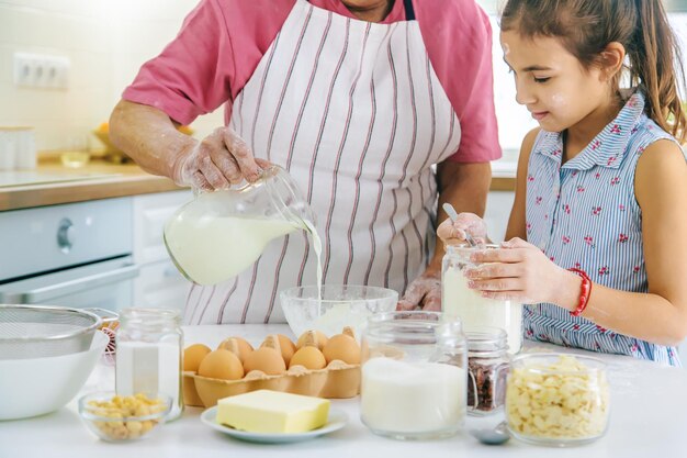 Criança e avó na cozinha preparam a massa na cozinha Foco seletivo