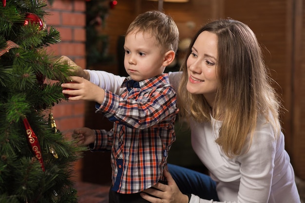 Criança e jovem pela árvore de natal