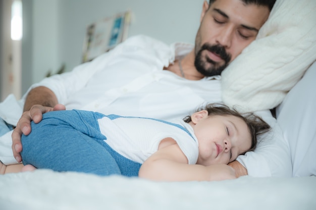 Criança e pai dormindo na cama