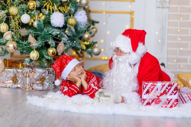 Criança e Papai Noel perto da árvore de Natal