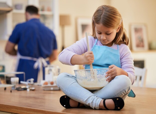 Criança e tigela para assar na cozinha na mesa com mistura de massa para biscoitos sobremesa ou receita de bolo Cozinhar criança ou preparar ingredientes para desenvolvimento de aprendizagem ou educação culinária em casa