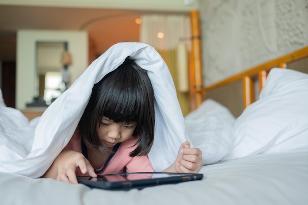 Criança é viciada em tablet garotinha jogando smartphone criança usa telefone assistindo desenho animado