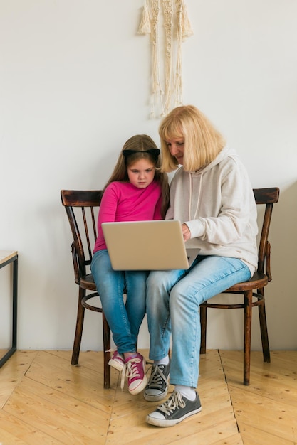 Criança e vovó usando laptop na cozinha. Conceito de geração e família.