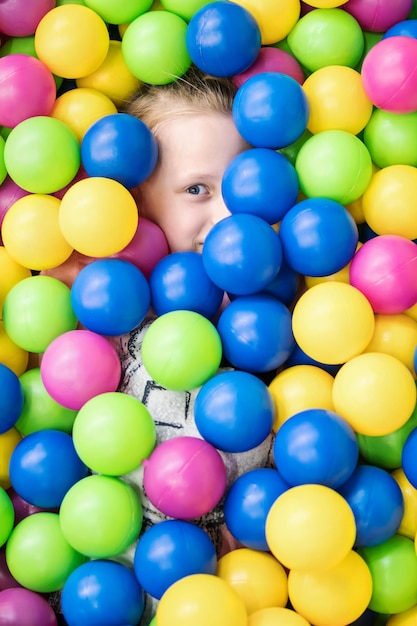 Criança em bolas coloridas para que apenas os olhos espreitam
