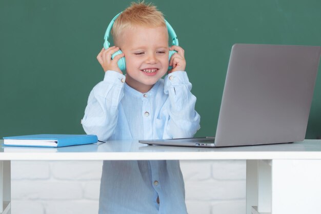 Criança em fones de ouvido usando um laptop e estudo on-line com o professor de videochamada no computador da escola
