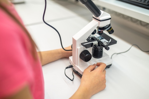 Criança em idade escolar perto de microscópio dentro de casa