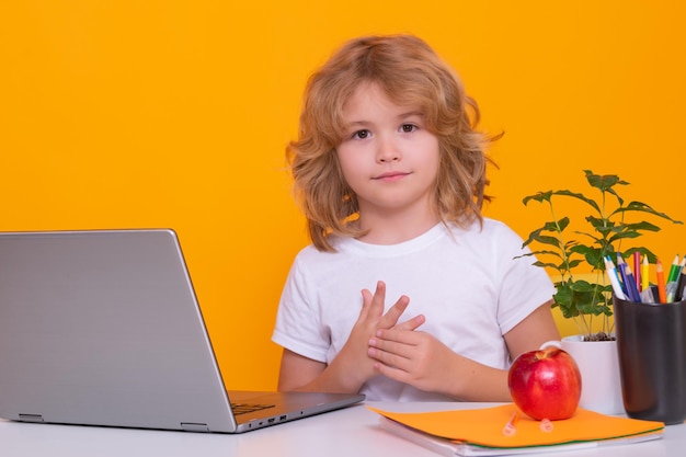 Criança em idade escolar usando computador portátil Menino de escola caucasiano inteligente aluno aluno voltando para a escola Educação crianças Menino de escola isolado no fundo amarelo do estúdio