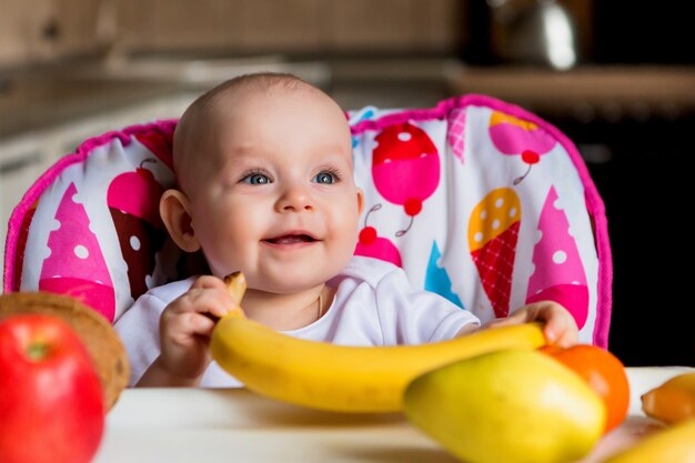 Criança, em, um, cadeira alta, comer, fruta, e, sorrindo