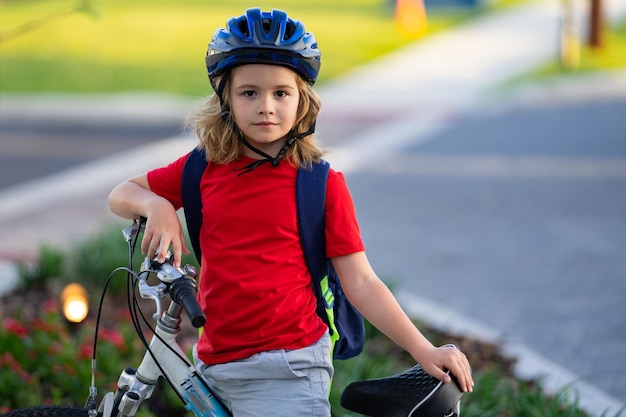 Criança em um menino de bicicleta em um capacete andando de bicicleta garotinho caucasiano bonitinho no capacete de segurança andando de bicicleta