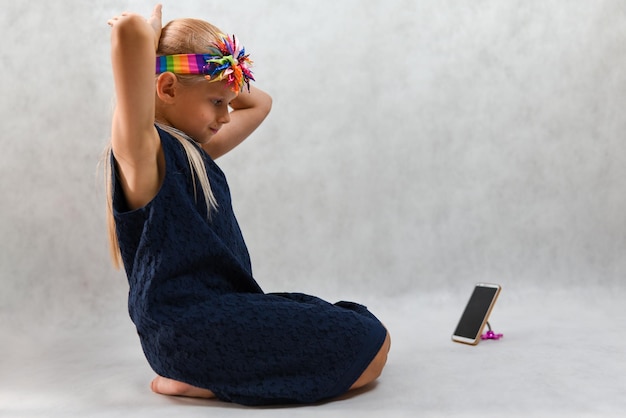 Criança em um vestido azul posando na frente de um smartphone