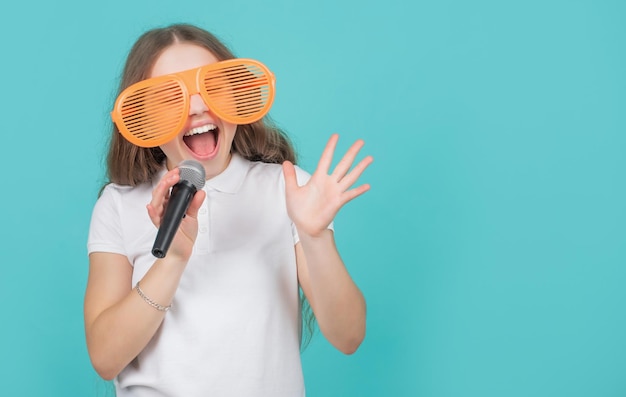 Criança emocional em óculos de festa engraçados cantando no microfone