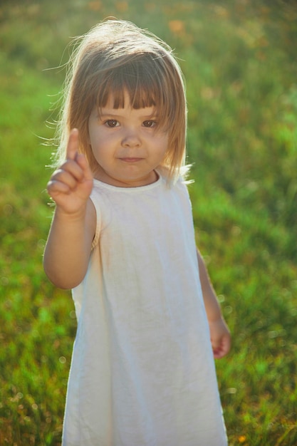 criança encantadora em vestido de linho andando no gramado