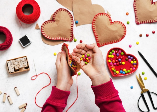 Criança enche o coração de papel com doces coloridos