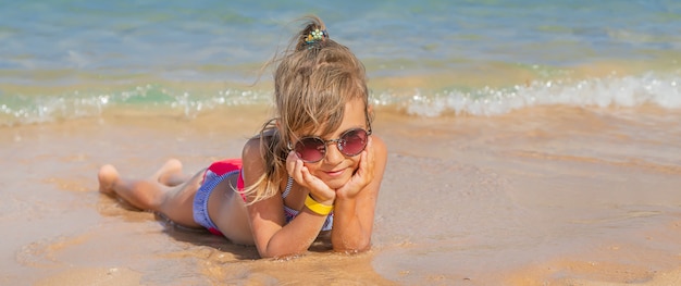 Criança encontra-se na areia na praia.