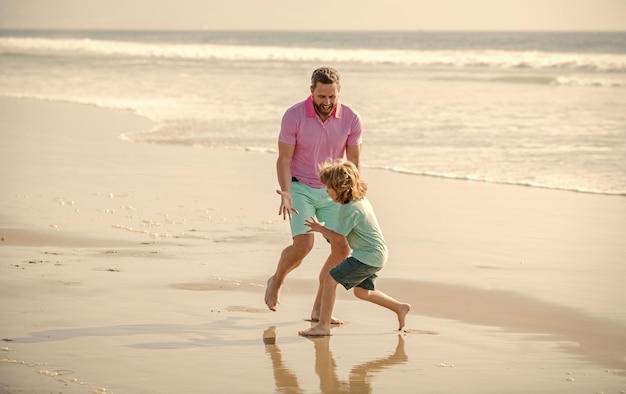 Criança engraçada e pai correndo na praia nas férias de verão juntos infância